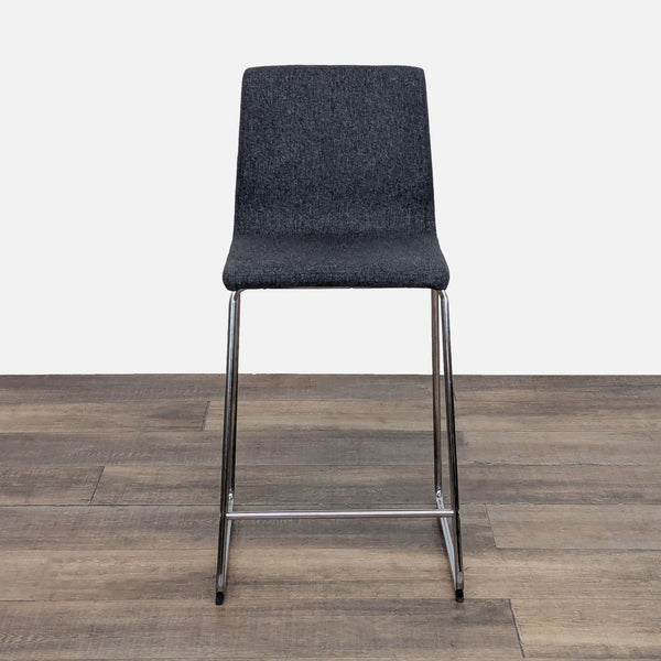 Gray upholstered stool with metal legs from Reperch, front view.