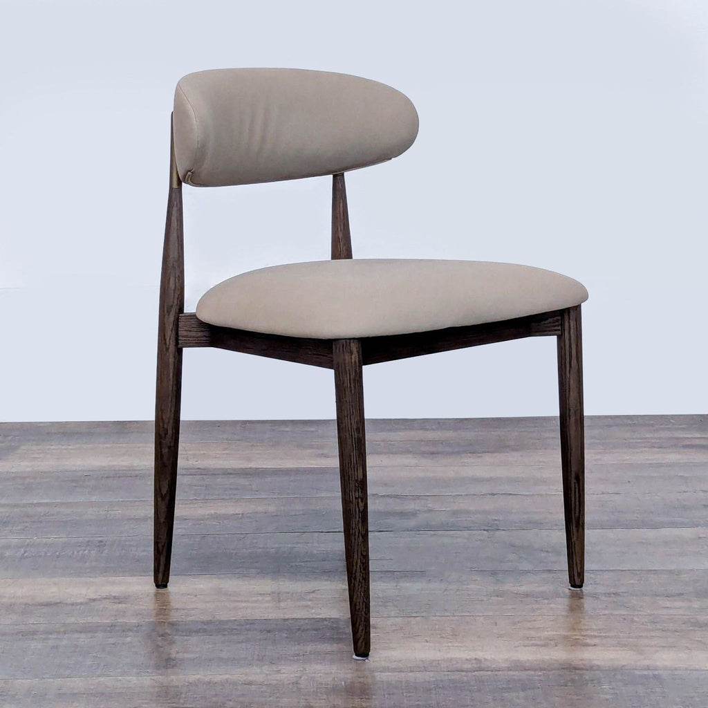 Side angle of an RH dining chair, showcasing sleek dark wood legs and a beige cushioned seat.