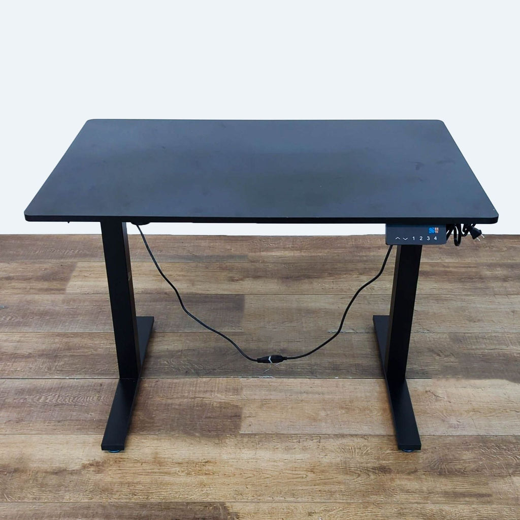 SHW desk with black veneer top and adjustable legs on a wooden floor.