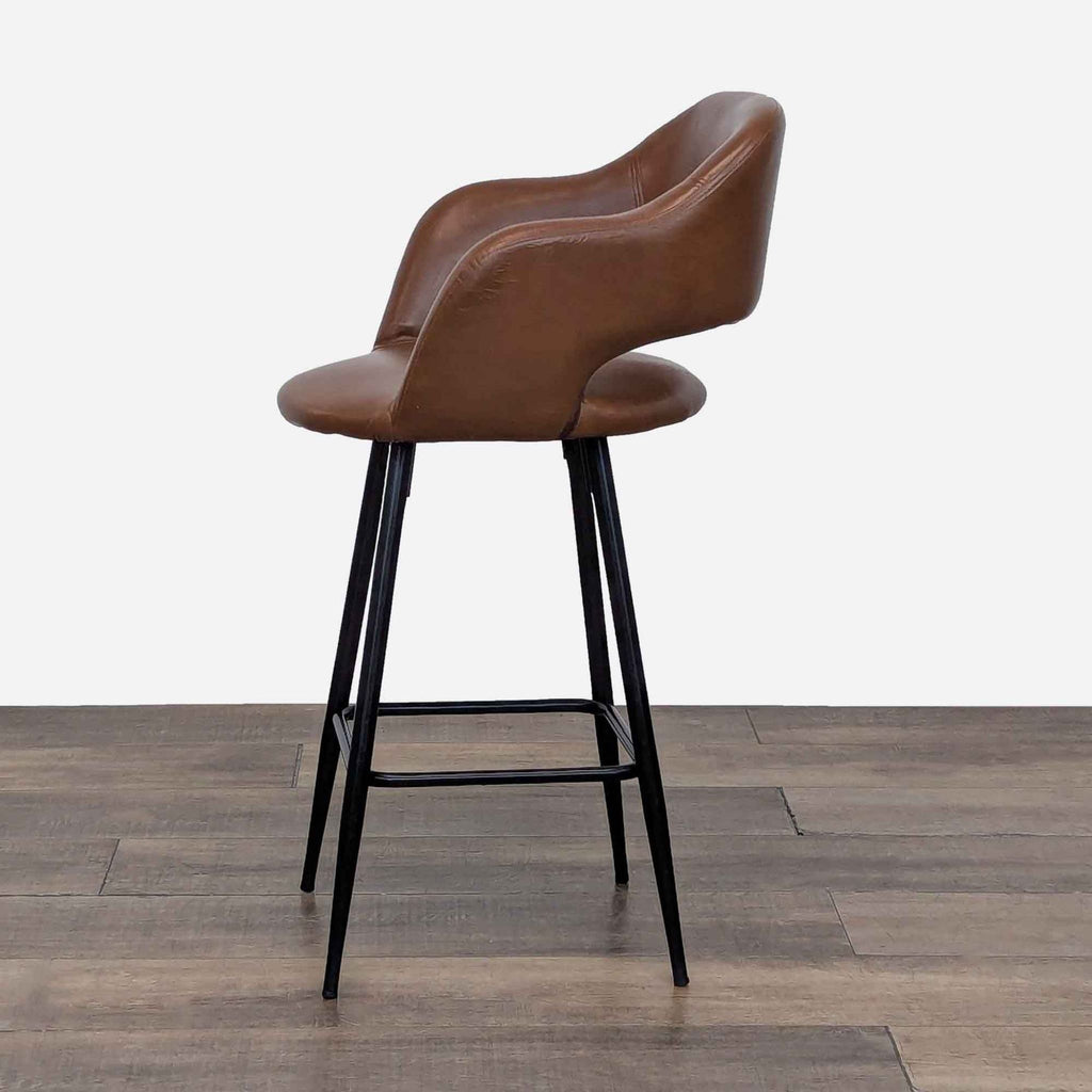 Side view of a brown leather stool with black metal legs and footrest.