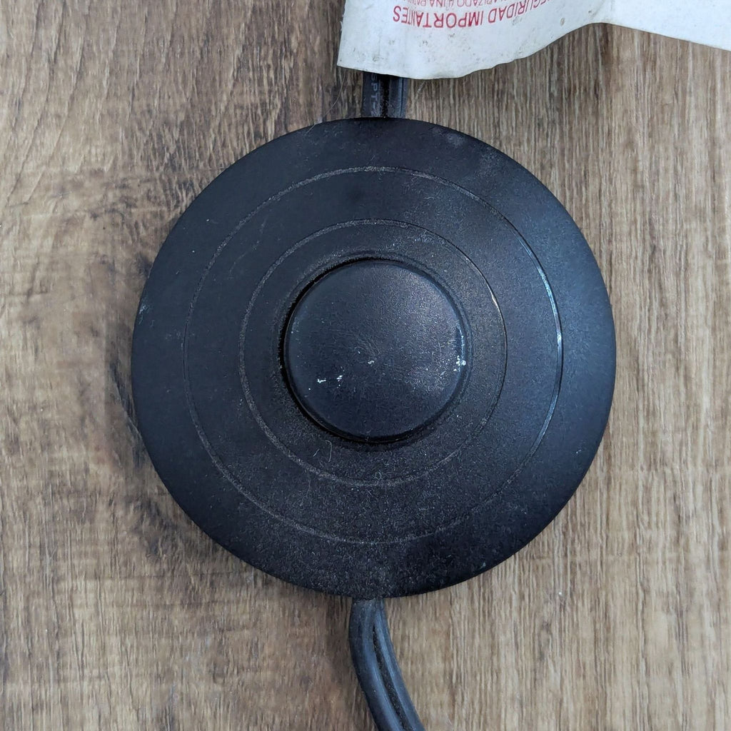 Round black foot switch on wooden floor for Reperch lighting.