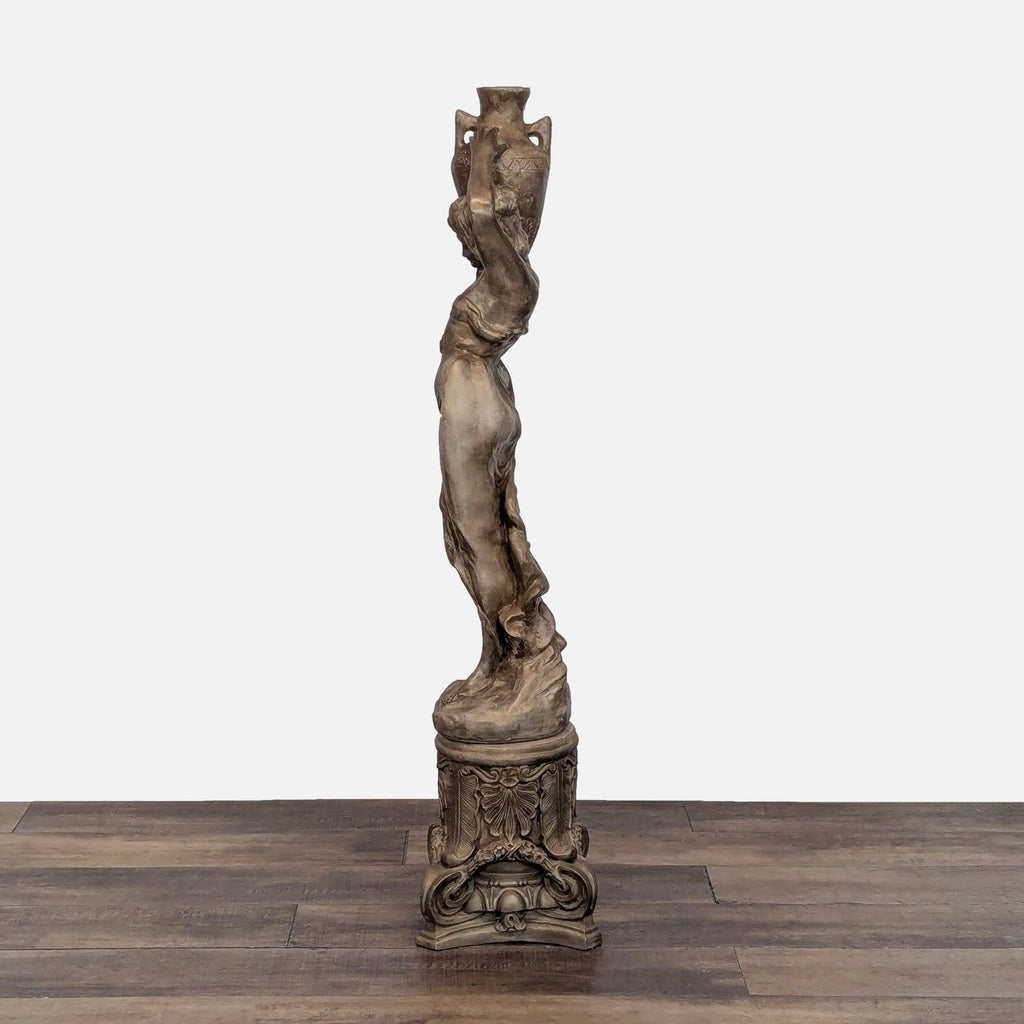 Classical-style woman sculpture with flowing garments, mounted on a decorative pedestal.