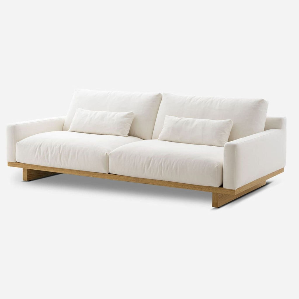 Angled view of a Castlery 3-seat sofa with feather cushions and wood base.