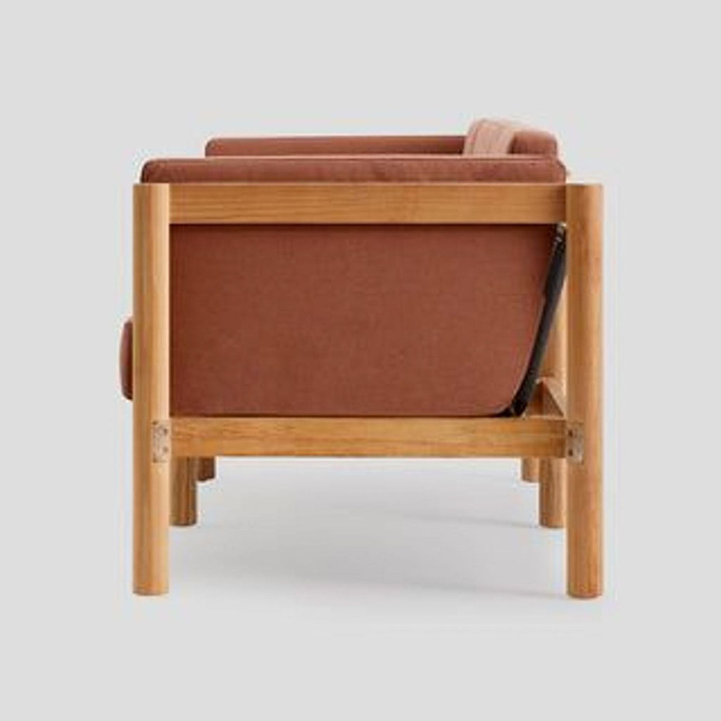 2. Side view of a rust-toned cushioned sofa showing teak wood frame and roped back design from Neighbor.