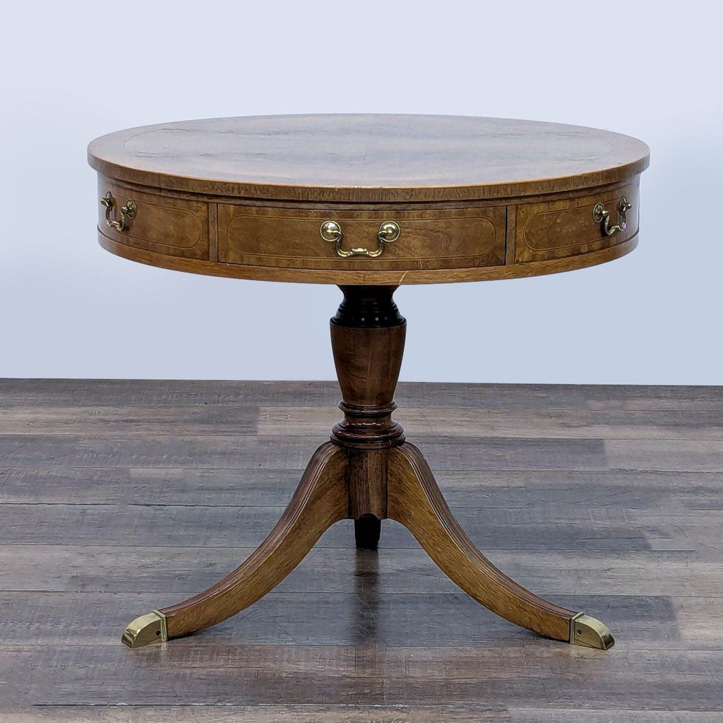 Baker Furniture side table with round top, two drawers, and brass accents on legs.