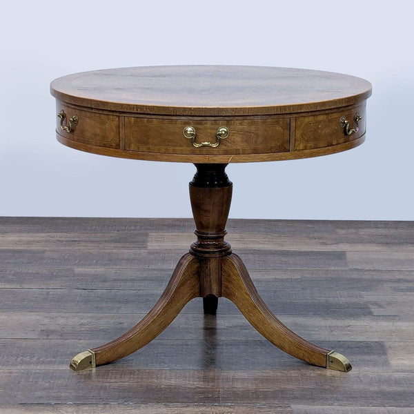 Baker Furniture side table with round top, two drawers, and brass accents on legs.