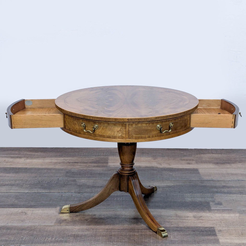 Round tabletop with burled and inlaid design, faux drawers, and brass capped splayed legs.
