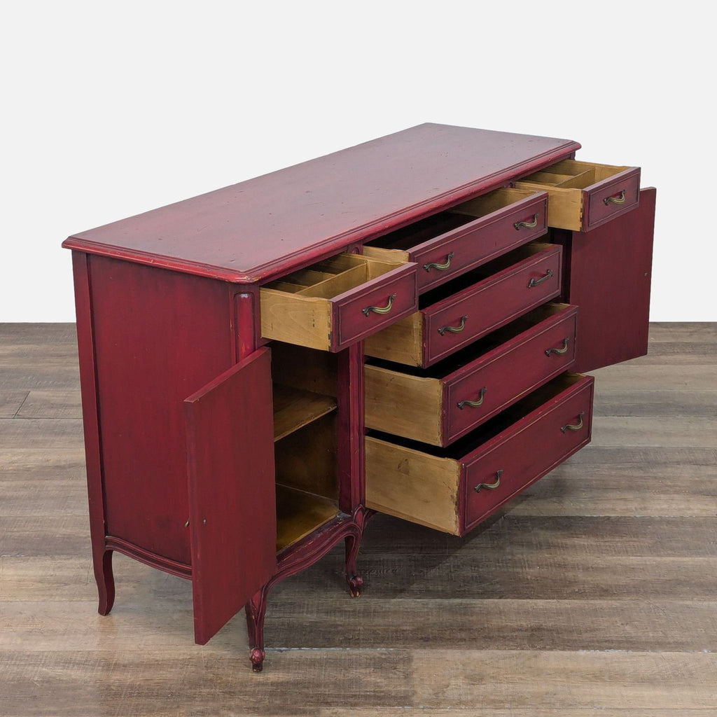 Open drawers and cabinets reveal spacious storage in a red sideboard.