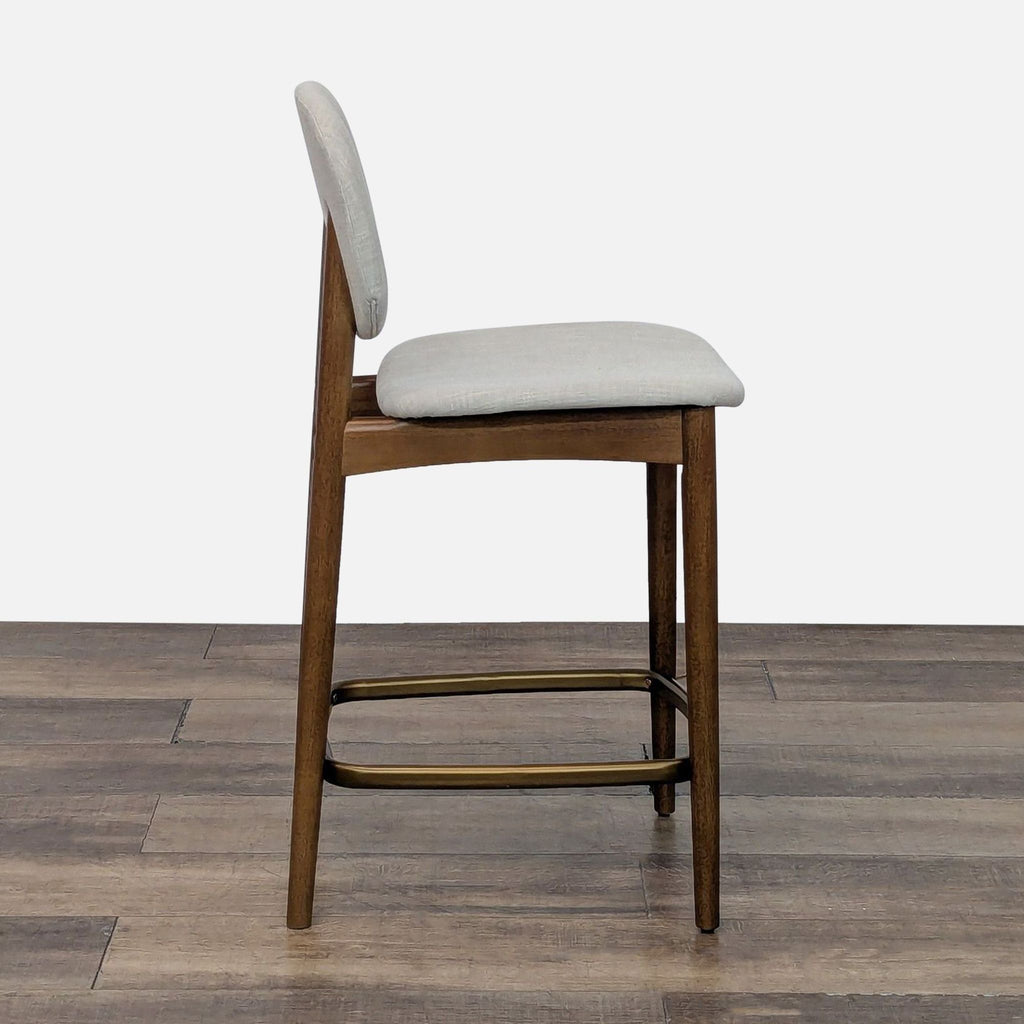 Side view of a fabric-upholstered stool featuring bent wood seat and back, with solid rubber wood legs.