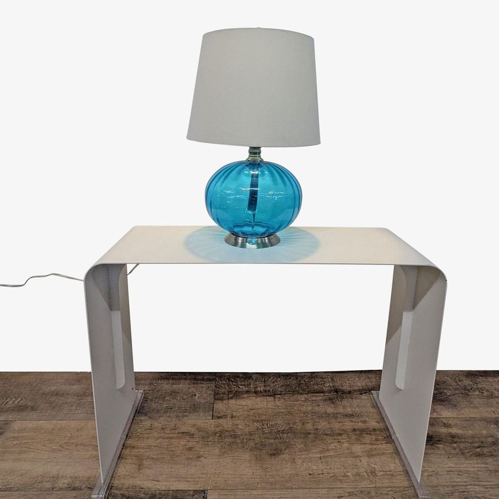 3. Full view of Pier 1 lamp with blue glass globe base and fabric shade, placed on a minimalist table.