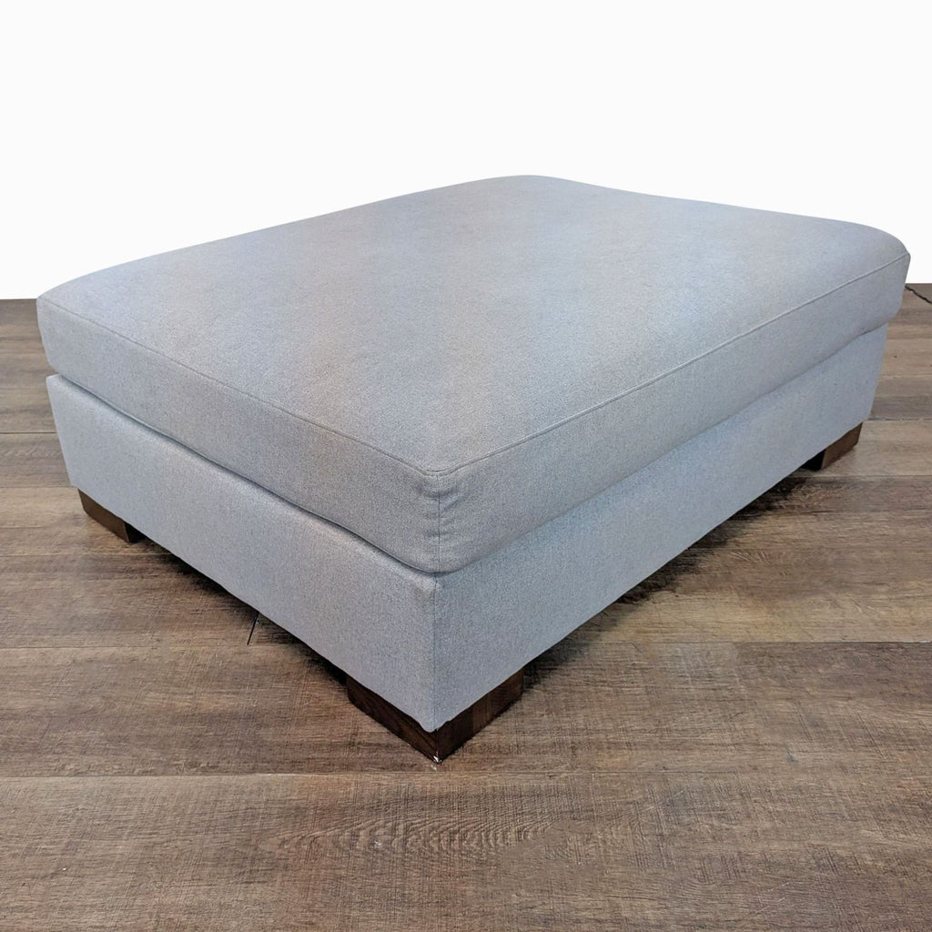 Rejuvenation Felton ottoman with cashmere flannel upholstery on wooden floor.