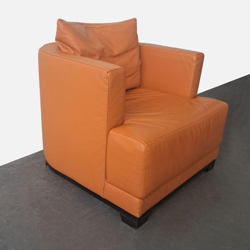2. Angled side view of an orange leather Natuzzi lounge chair with curved back and track arms.