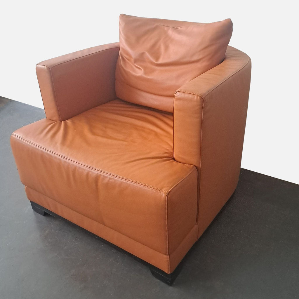 3. Natuzzi orange leather lounge chair featuring track arms and a curved back, shown from an alternate angle.