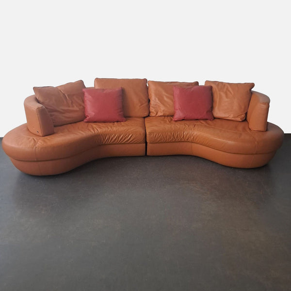 1. Modular semicircular Natuzzi sofa in leather with curved seats and four reddish pillows, category Other.