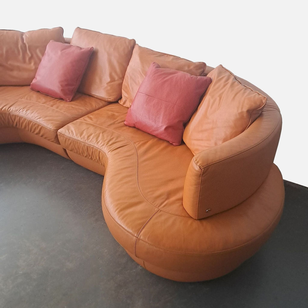 3. Close-up of sectional Natuzzi sofa with tan leather upholstery and soft reddish pillows, category Other.
