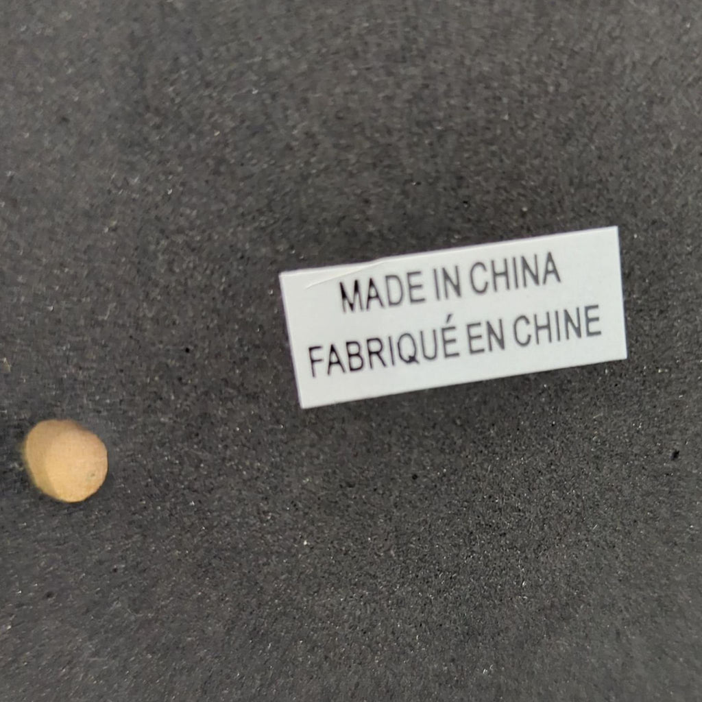 Close-up of a label reading "Made in China / Fabriqué en Chine" on a dark textured surface.