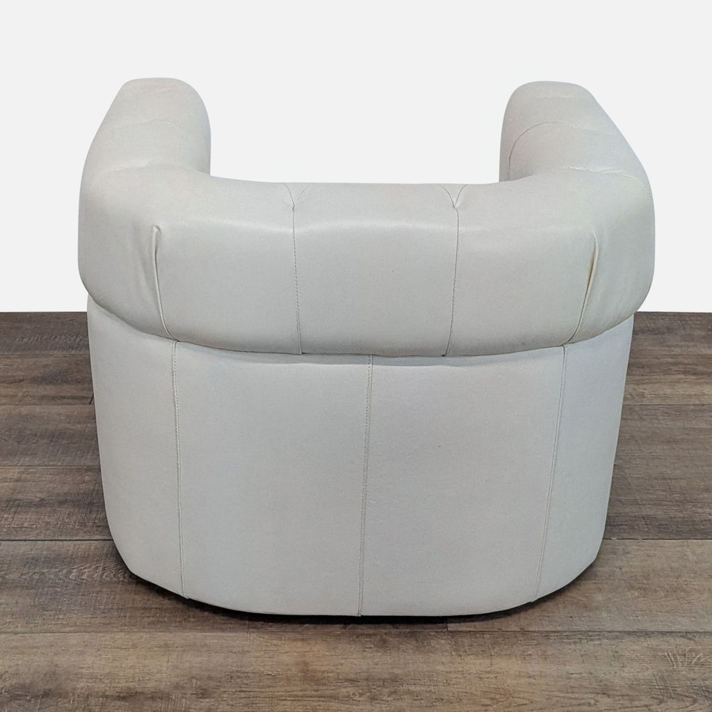 2. Rear view of a West Elm lounge chair with curved back and smooth white leather upholstery.