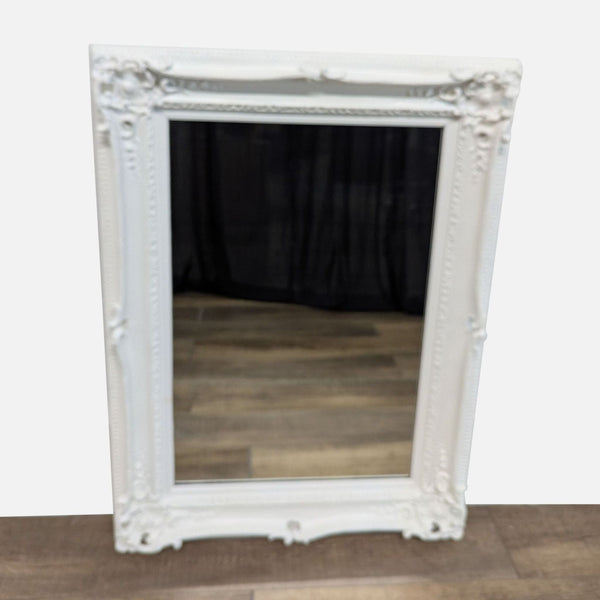 Elegant white Reperch mirror with ornate frame and wooden floor reflection.