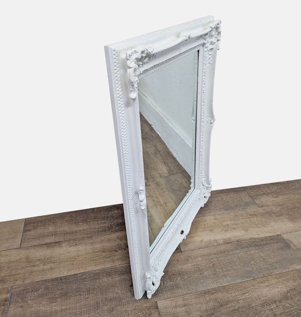 Side view of a white-framed Reperch mirror against a wooden floor.