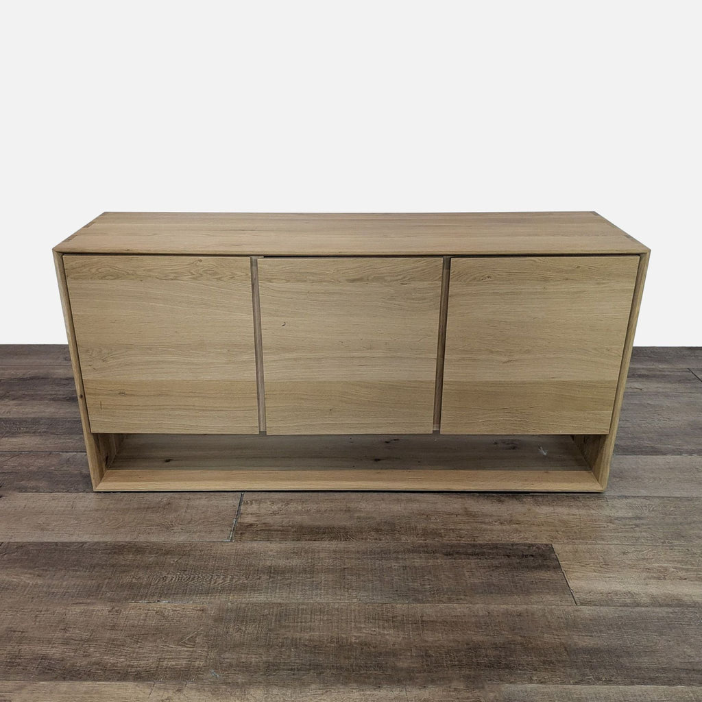 Reperch wooden sideboard with three closed doors on a wooden floor.