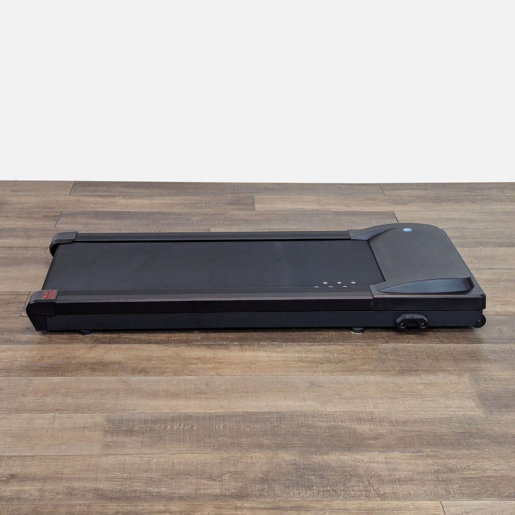 1. Lifespan under desk treadmill, compact black walking pad on wooden floor, ideal for home or office use.
