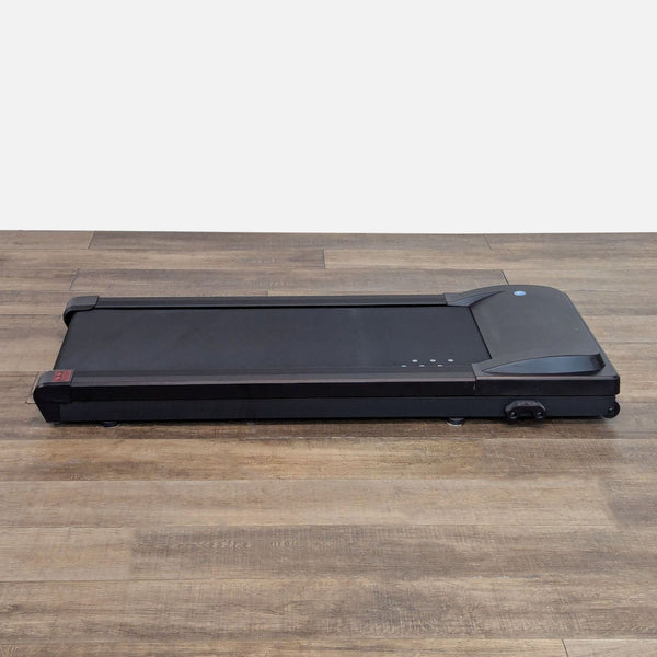1. Lifespan under desk treadmill, compact black walking pad on wooden floor, ideal for home or office use.