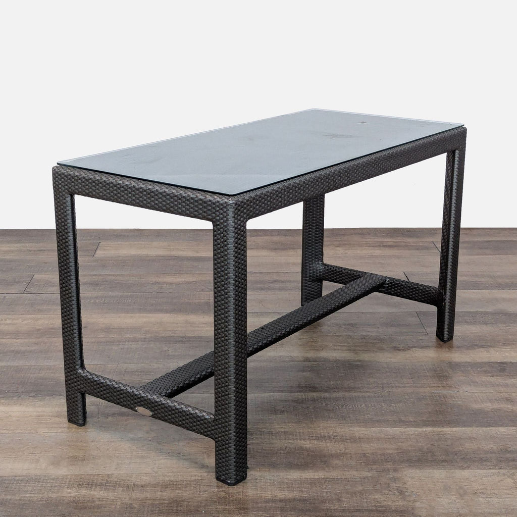 2. Close-up of a rectangular hand woven rattan outdoor table with a glass protective top from the Dedon set.