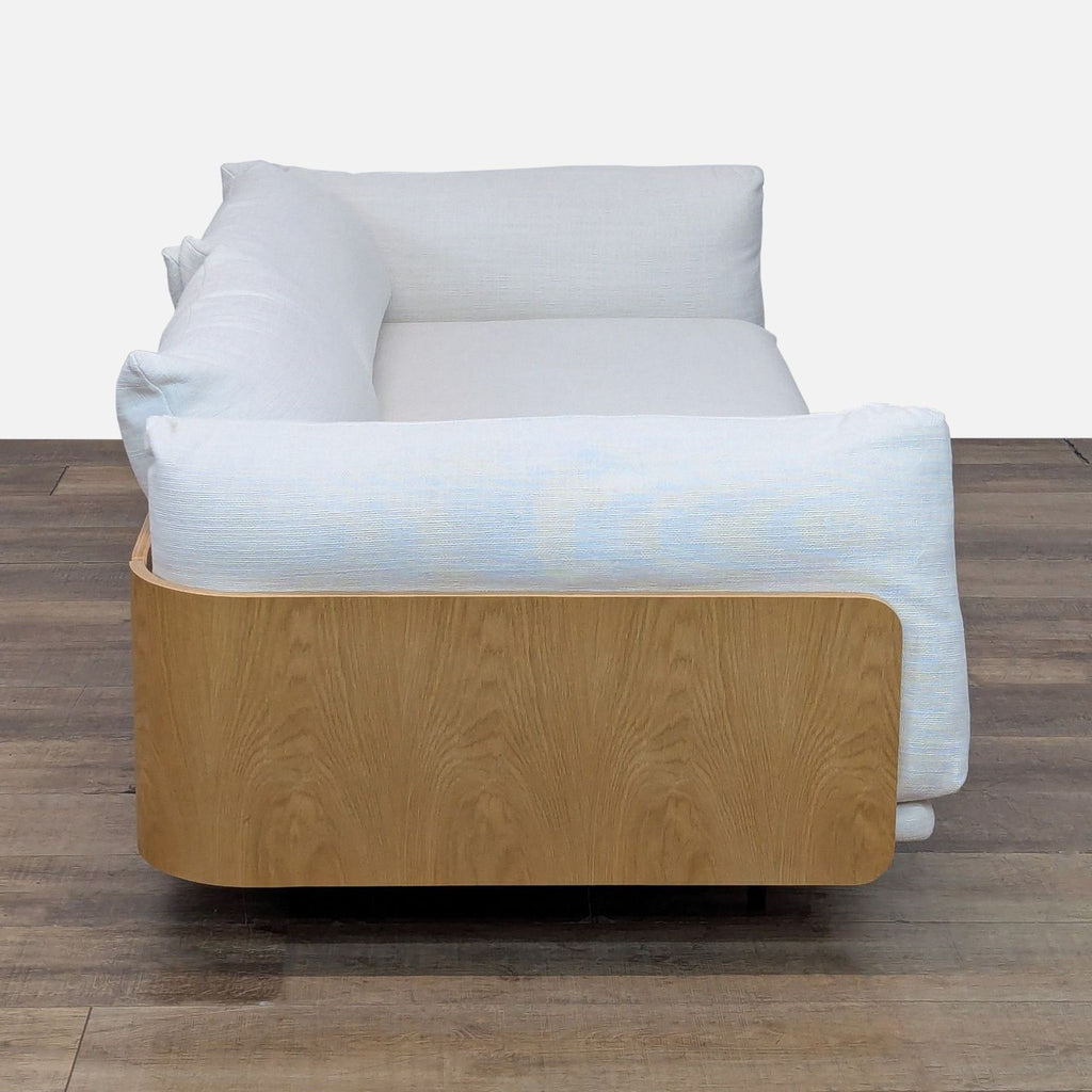 Side view of a Design Within Reach 3-seat sofa, highlighting its curved wood frame and oversized white cushions.