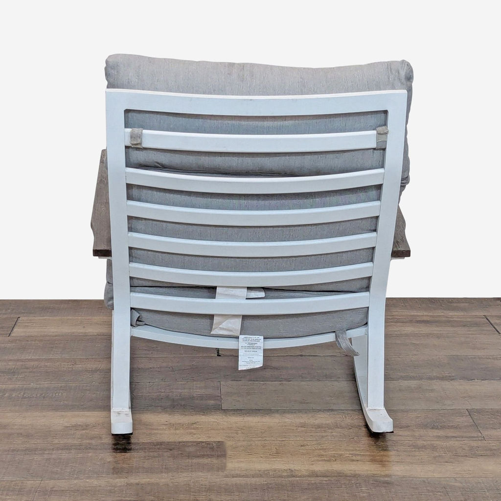 3. Back view of a padded Article rocking chair with a white aluminum slatted frame and thick seat cushion.