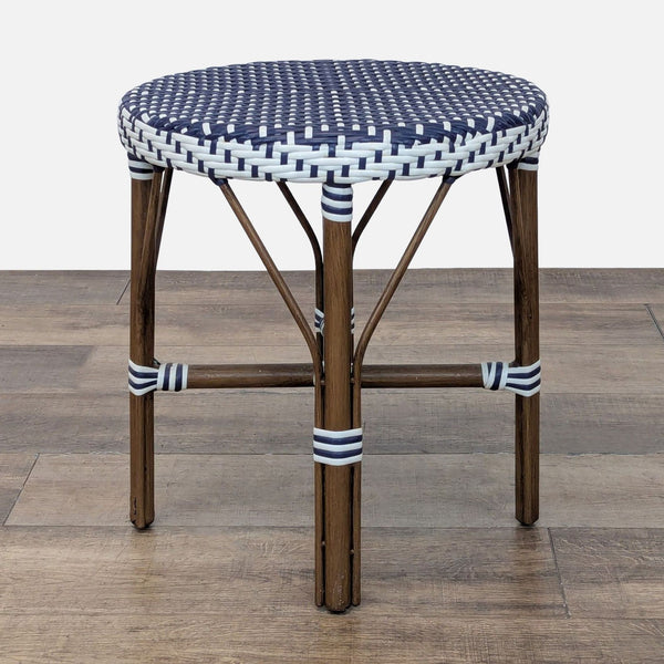 1. Small round outdoor table by Reperch with a wood frame and blue and white rattan top, side view.