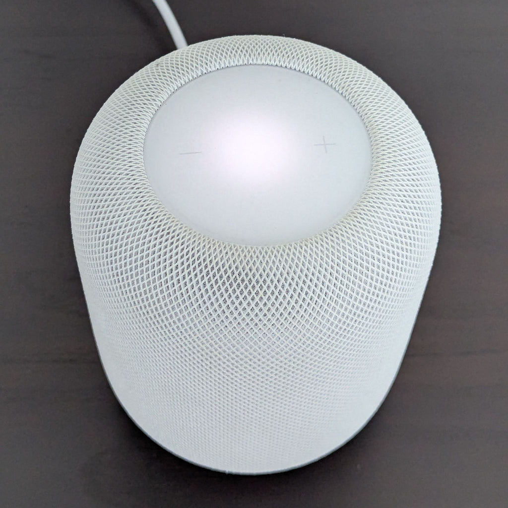 Top-down view of a white Apple HomePod with illuminated touch controls, placed on a dark table.