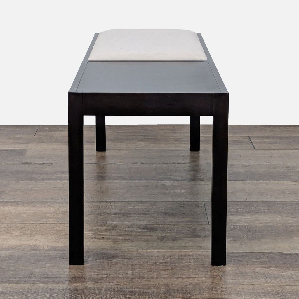 2. Side view of a Crate & Barrel wood bench featuring a partial faux leather cushion seat.