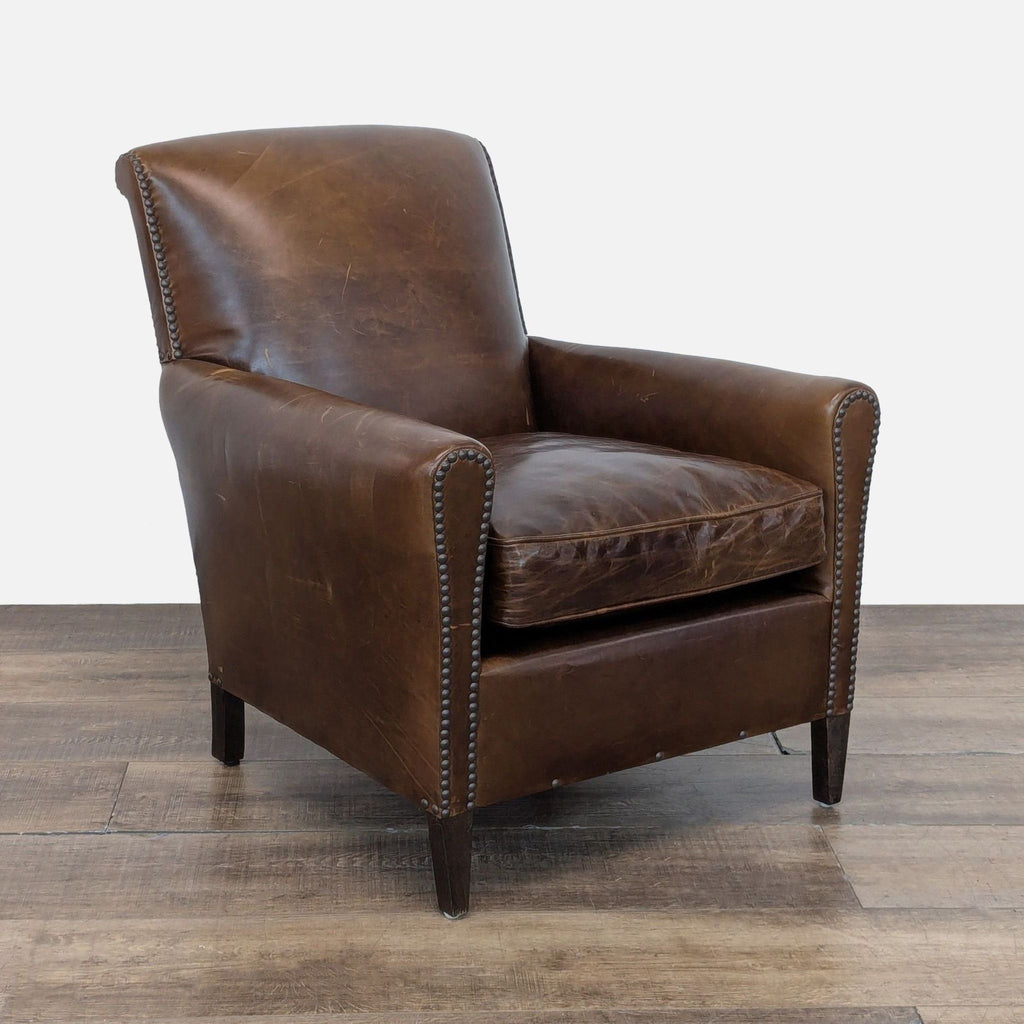 3. Angled view of a Restoration Hardware lounge chair highlighting nailhead trim and worn brown leather.