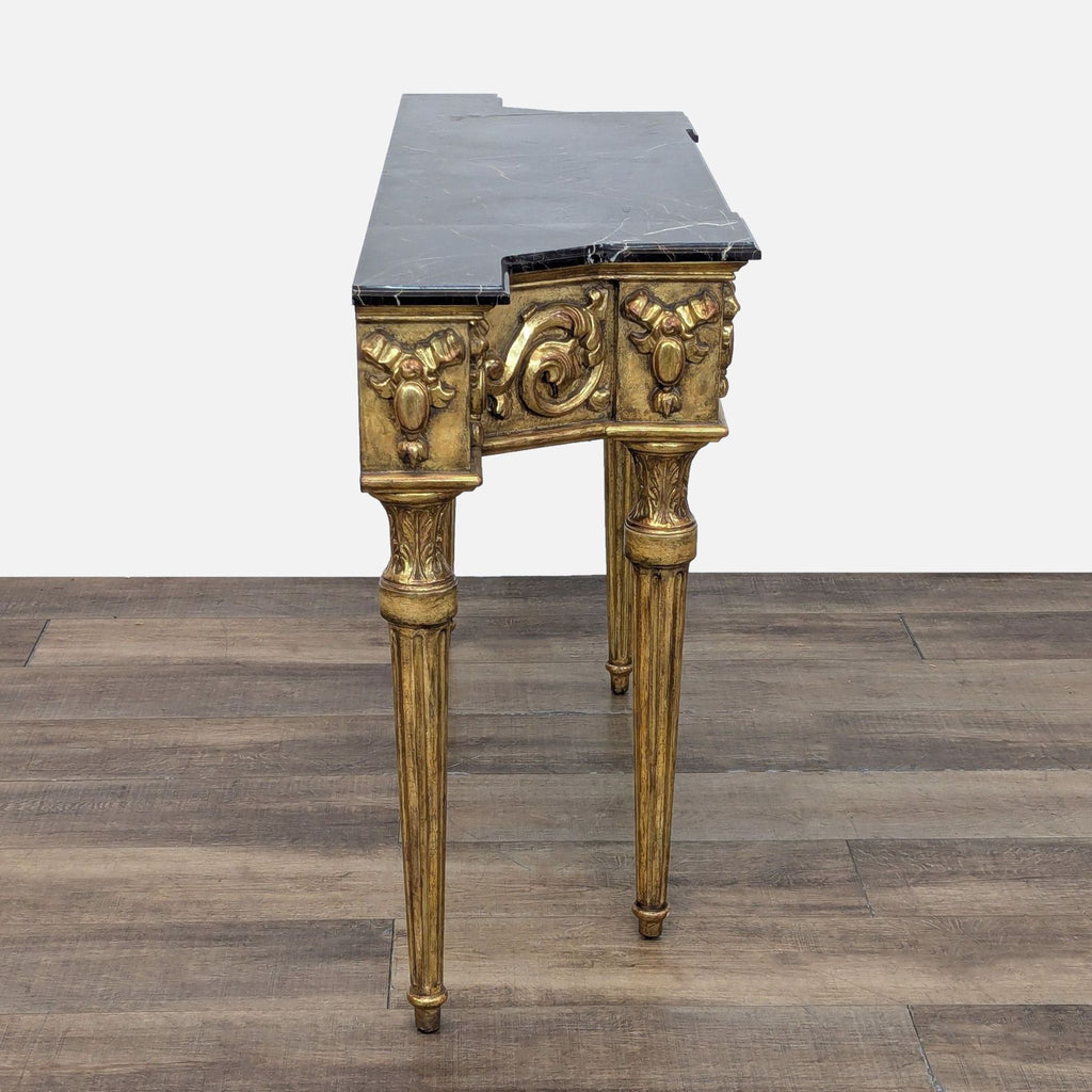 3. Side profile of a gilded, carved console table with fluted legs and black marble top, elegant design.