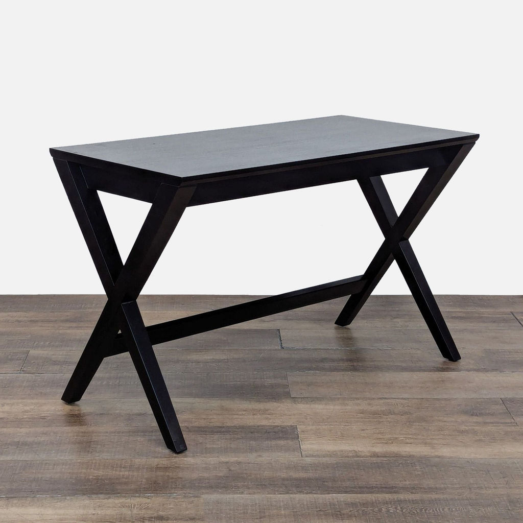 3. Angled view of a Crate and Barrel desk, highlighting its crossed black legs and sleek, minimalist design.