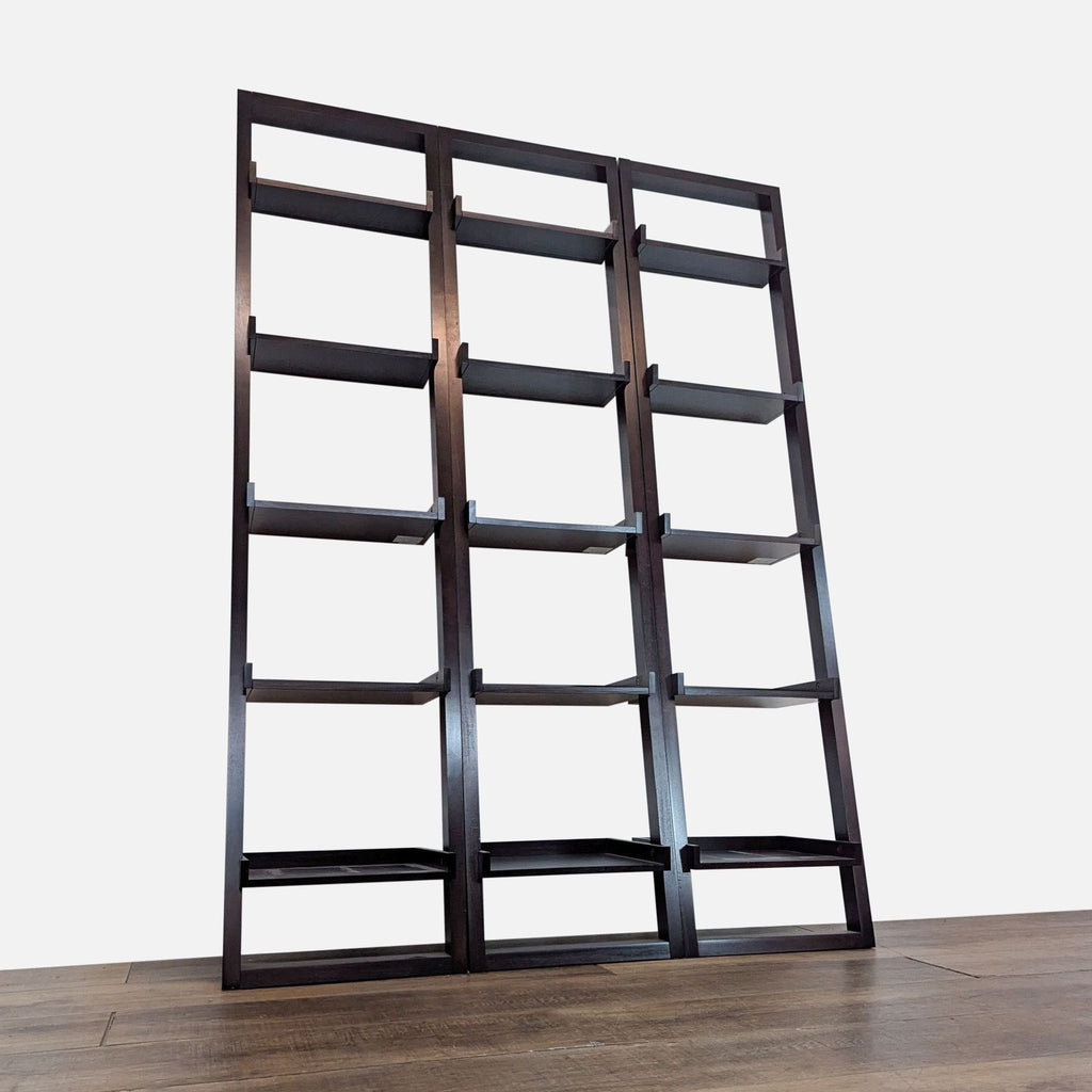 3. Low-angle shot showing three black Crate & Barrel bookcases with solid shelves and modern deep shelf fronts.