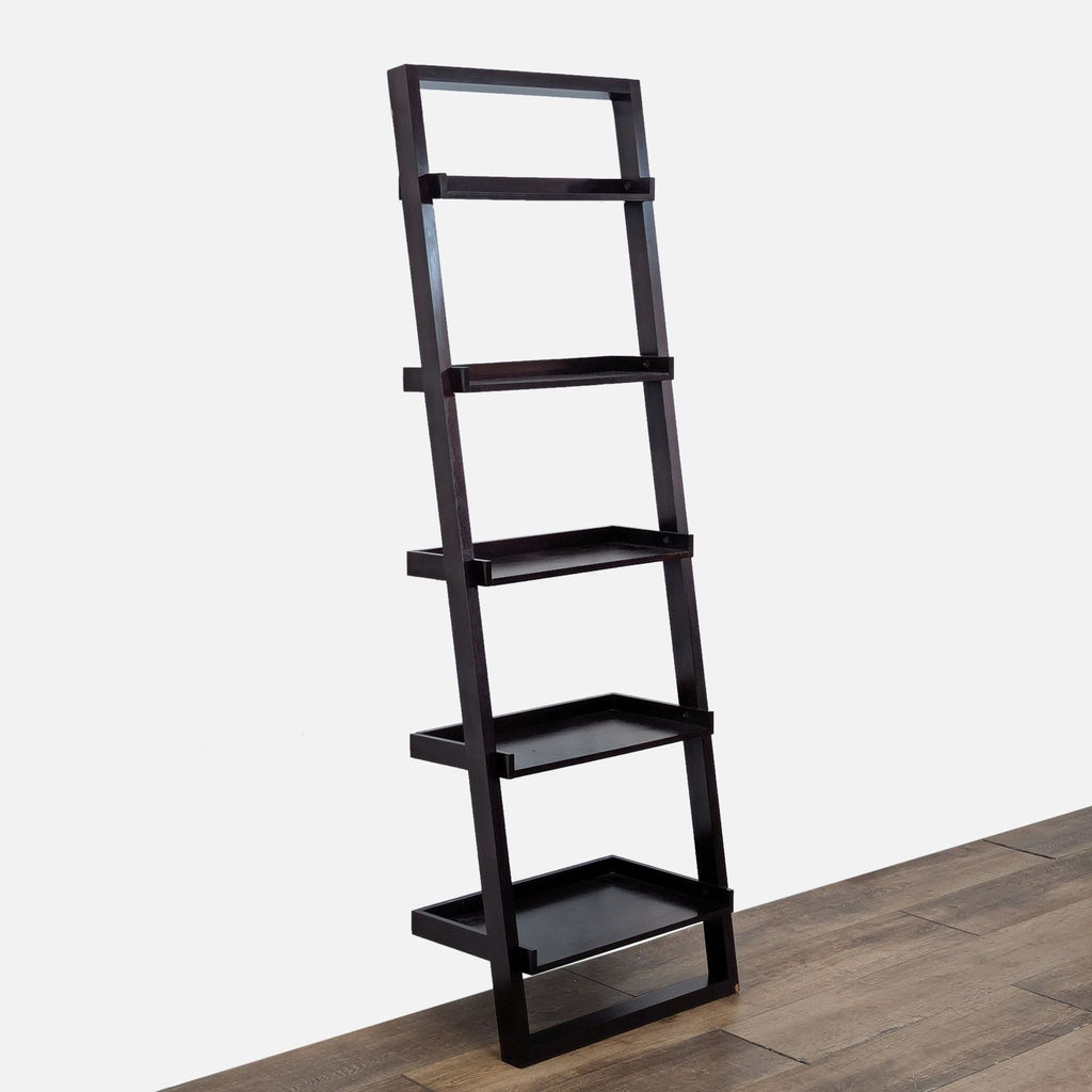 2. Angled side view of a Crate & Barrel solid black hardwood bookshelf with five sturdy shelves on wood flooring.