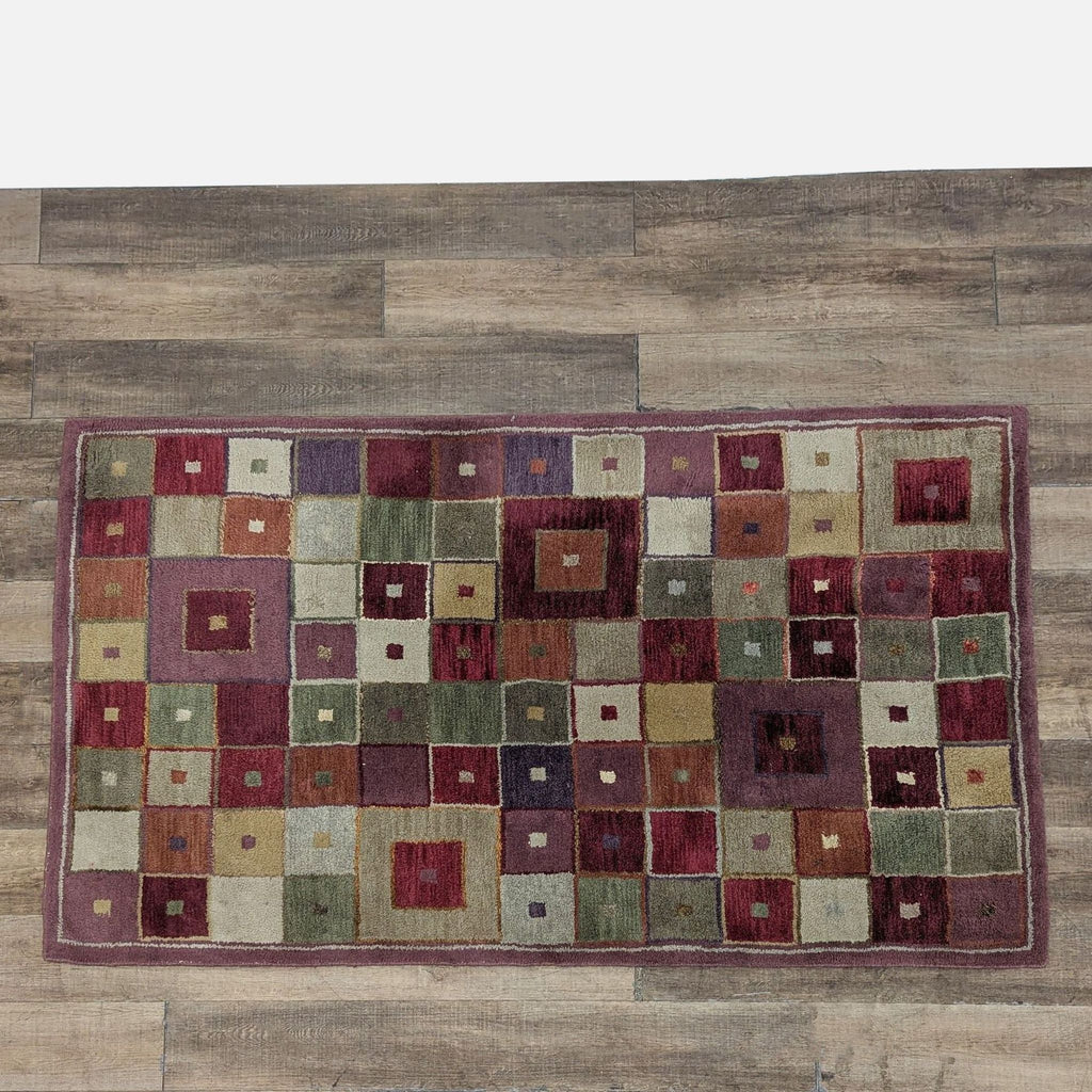 Hand tufted wool Pottery Barn rug with a colorful geometric square design on a wooden floor.
