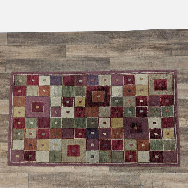 Hand tufted wool Pottery Barn rug with a colorful geometric square design on a wooden floor.