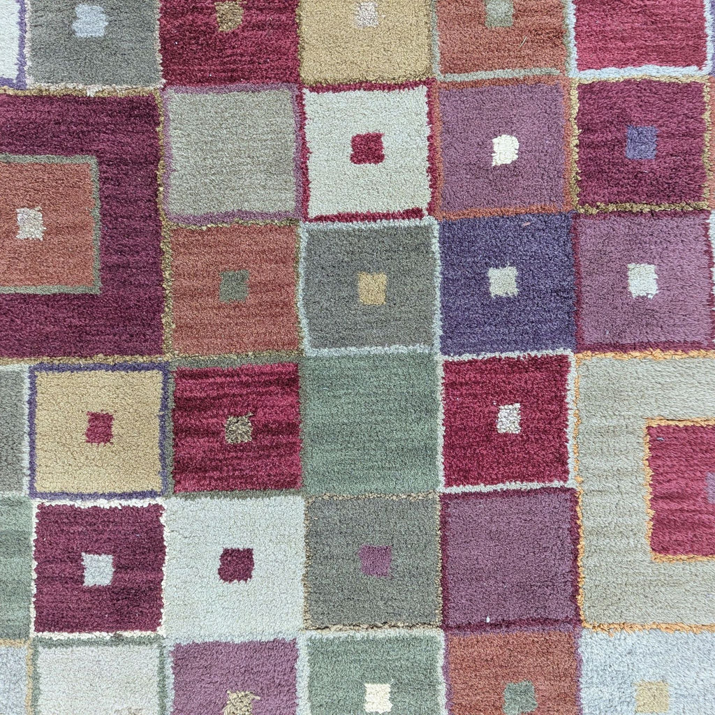 Close-up view of Pottery Barn wool rug, showing geometric pattern of multicolored squares.