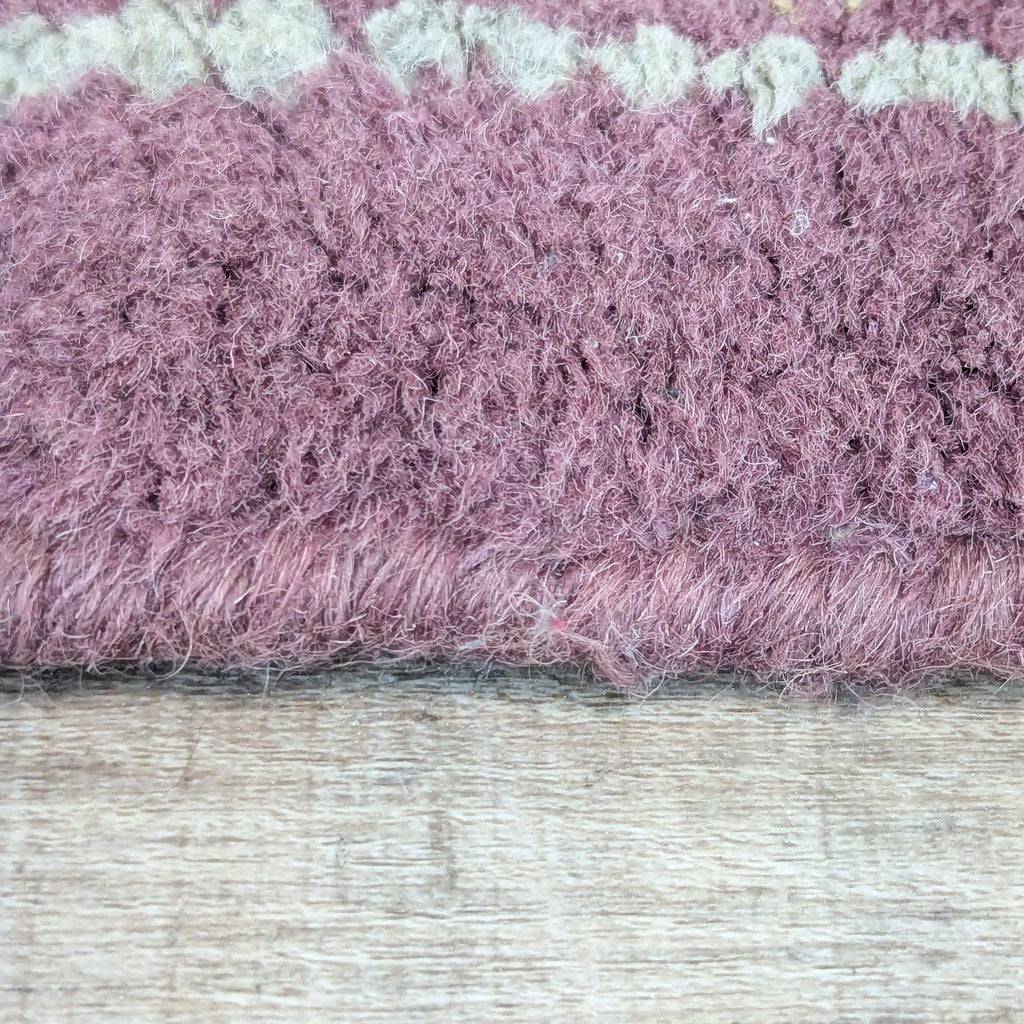 Detailed shot of the edge of a hand tufted Pottery Barn wool rug, highlighting its thick texture.