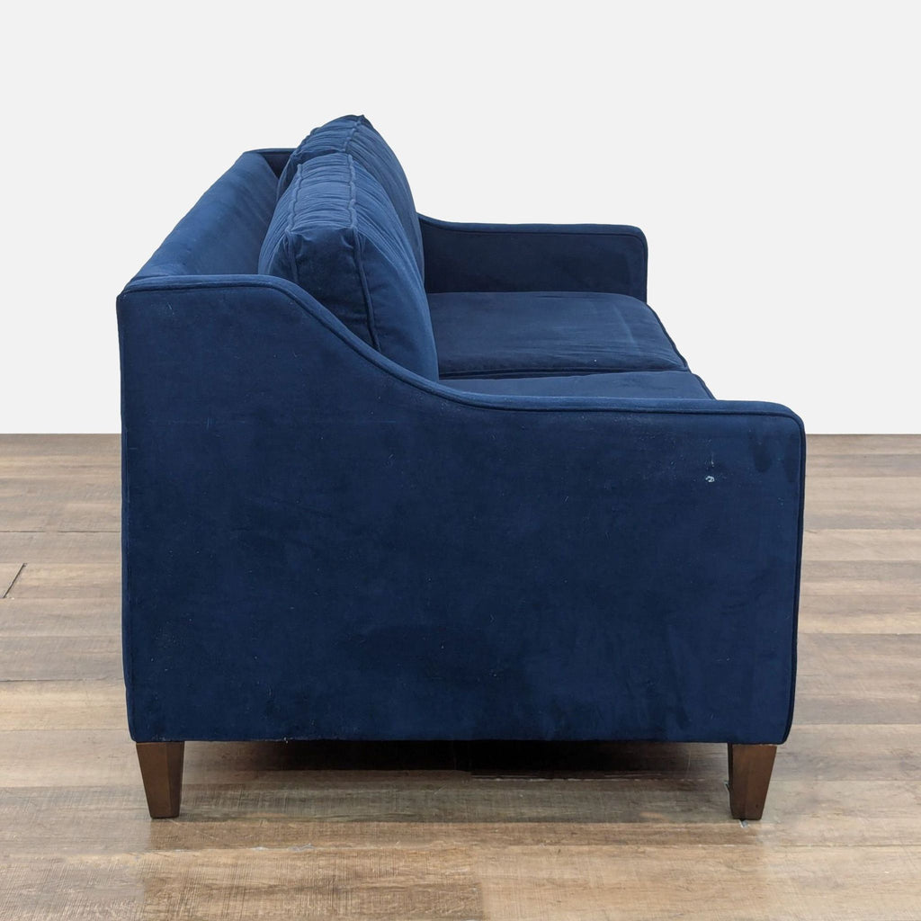 Side view of a blue velvet West Elm sleeper sofa with wooden legs and plush cushions, category: Sleeper Sofa.