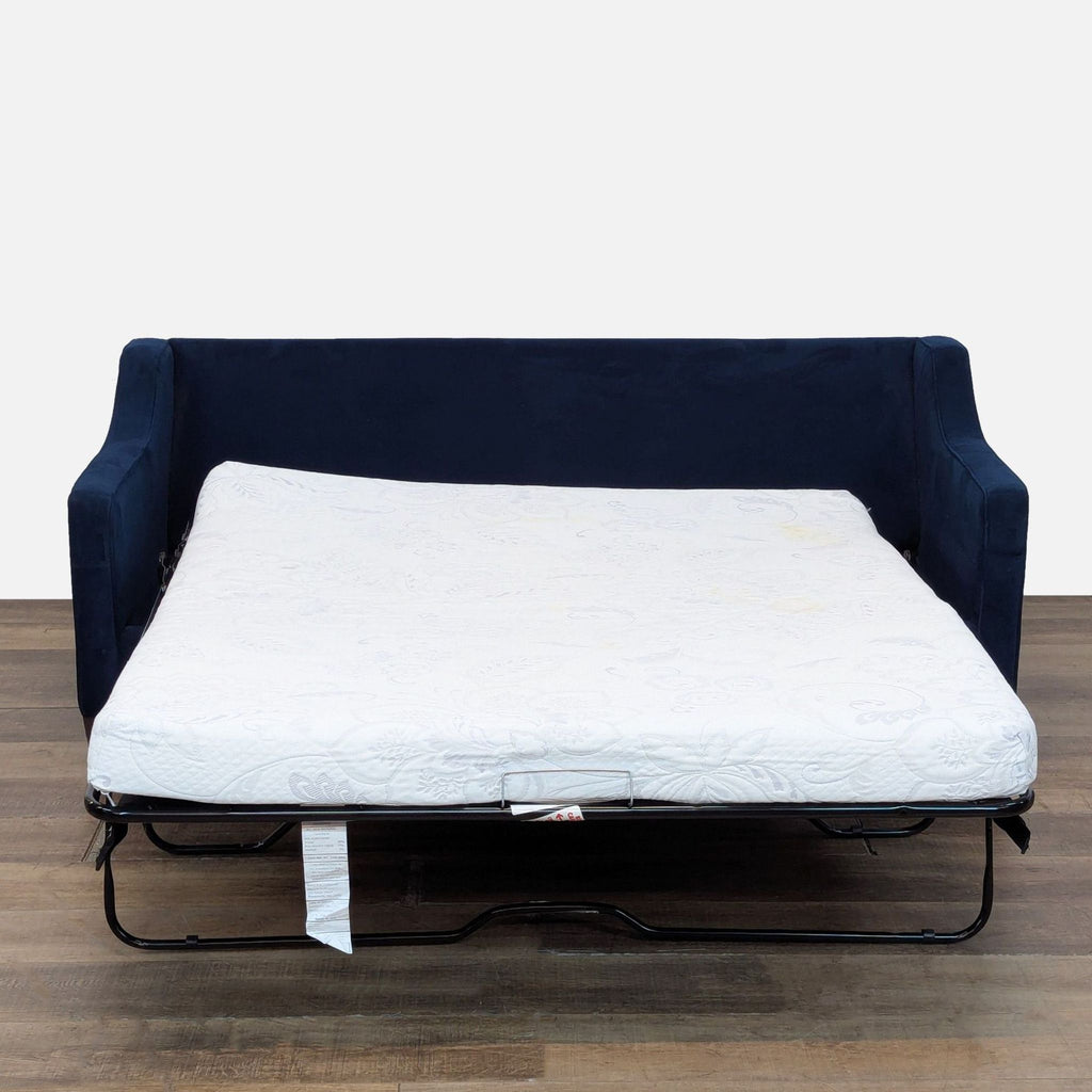 West Elm sleeper sofa pulled out to reveal a memory foam mattress, showing its functionality on a wood floor.