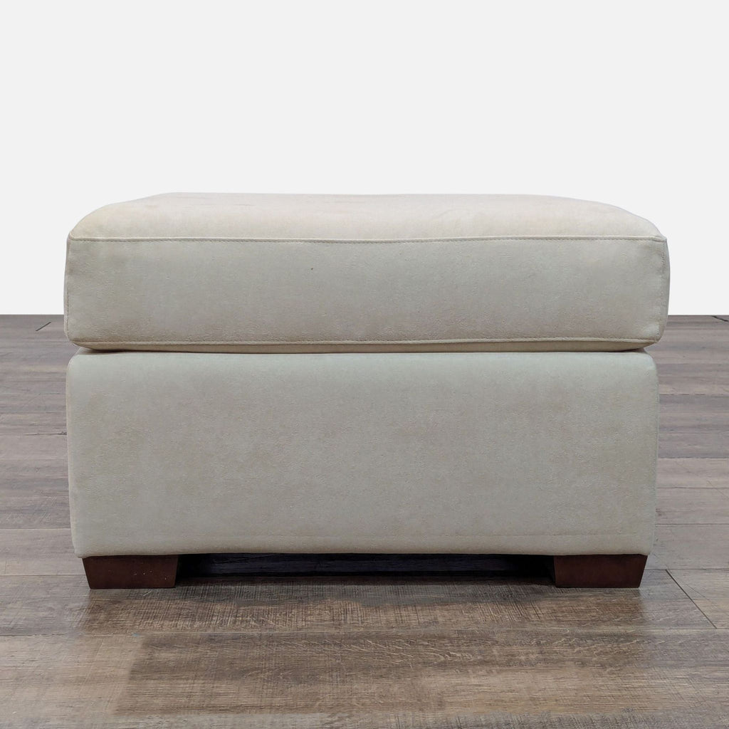 2. Front view of a plush, light-colored American Leather ottoman with simple lines and wood block feet.