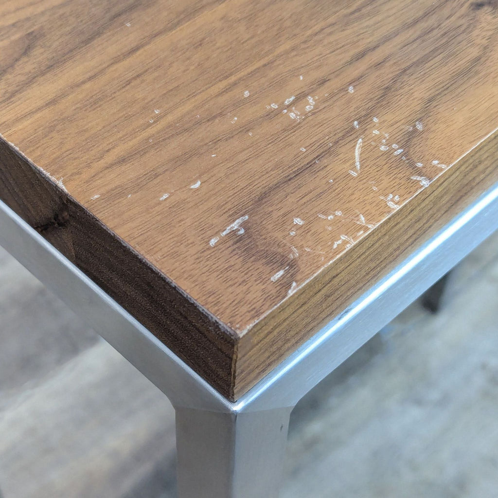 3. Close-up of Room & Board table corner showing wood scratches and brushed metal frame detail.