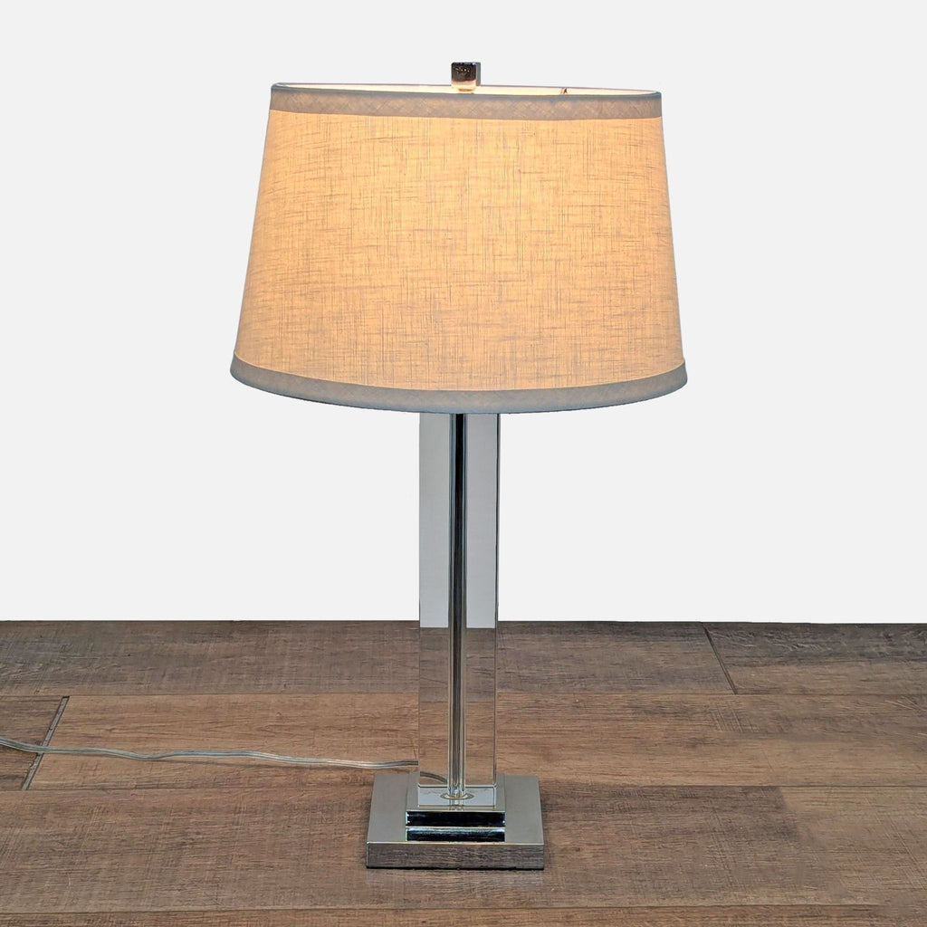 1. Restoration Hardware lamp with a clear glass column, aluminum base, and drum linen shade, lighting category.