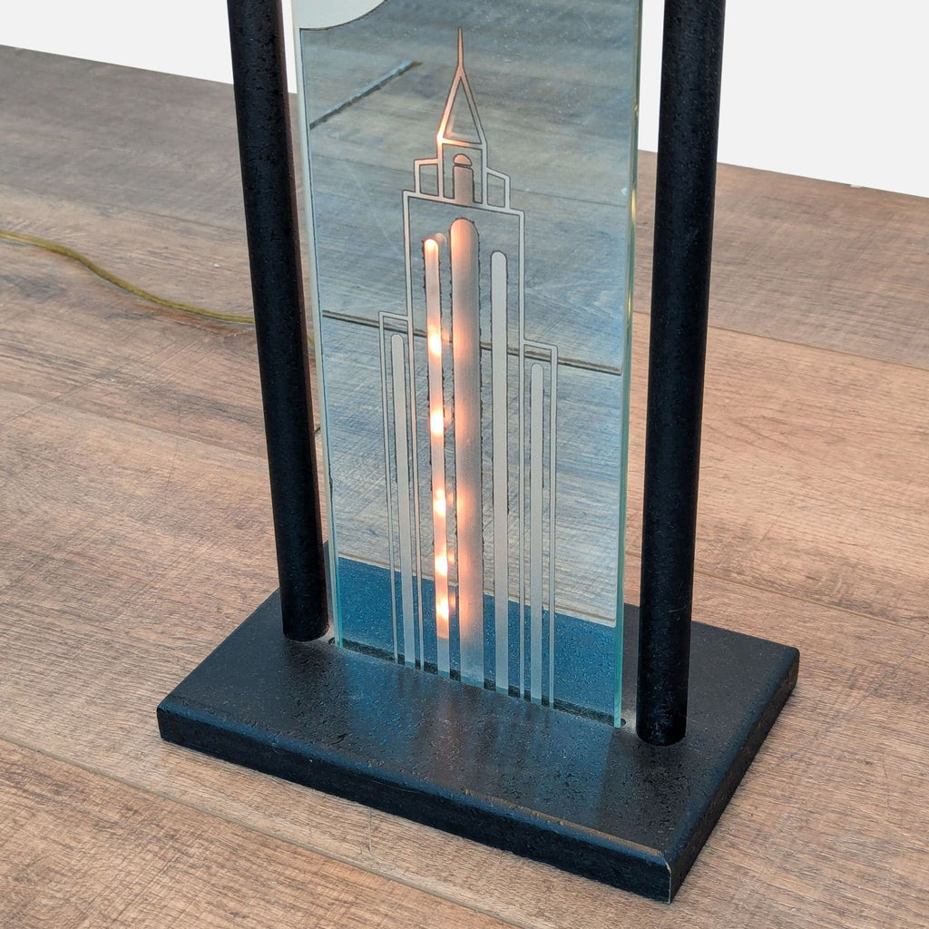 2. Close-up of Reperch lamp’s glass panel, showing building etching and glowing rope light on the metal base.