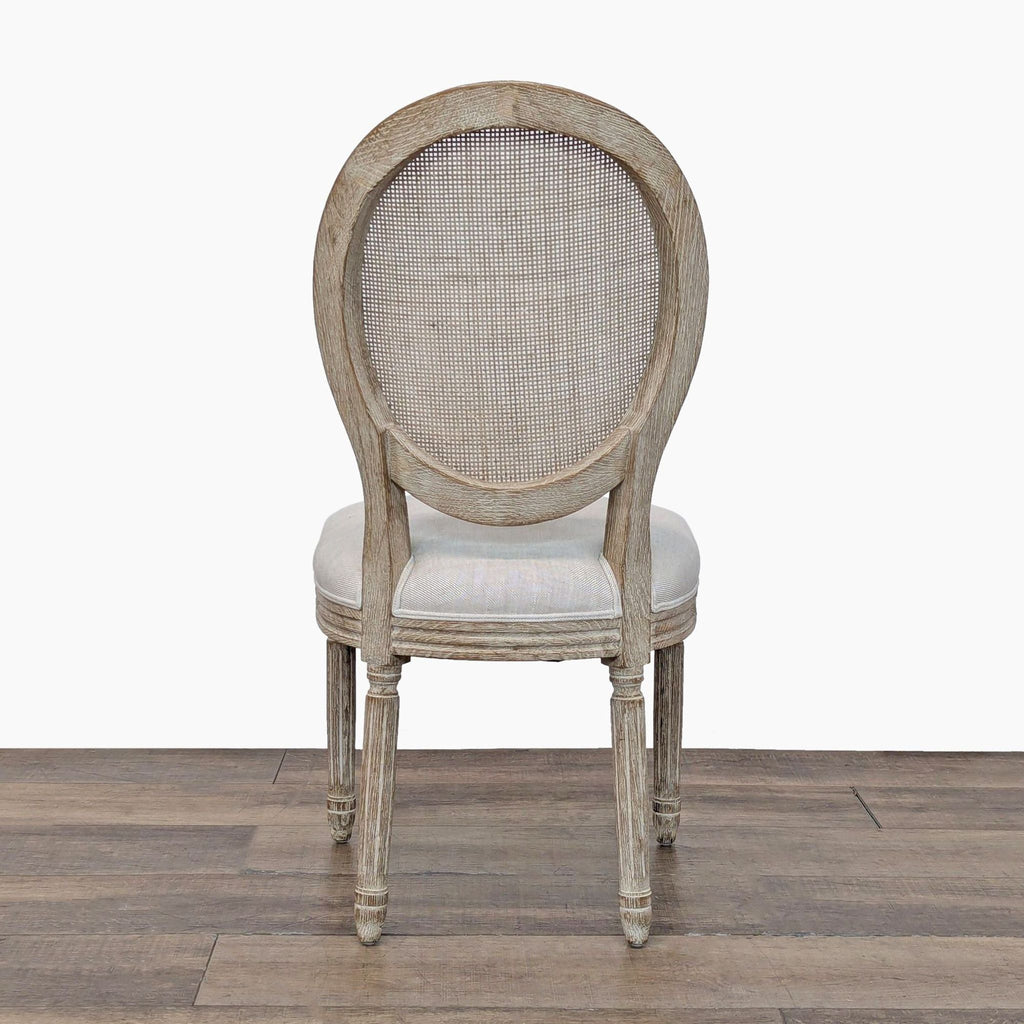 Rear view of a vintage-inspired French dining chair featuring a round caned back and fluted oak legs.