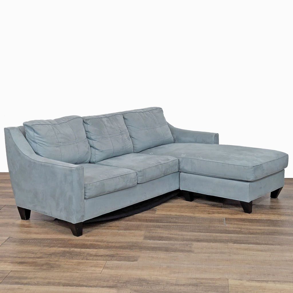 3. Angled view of Cindy Crawford Home sectional sofa in blue, showing tufted cushions, sloped arms, and wood feet.