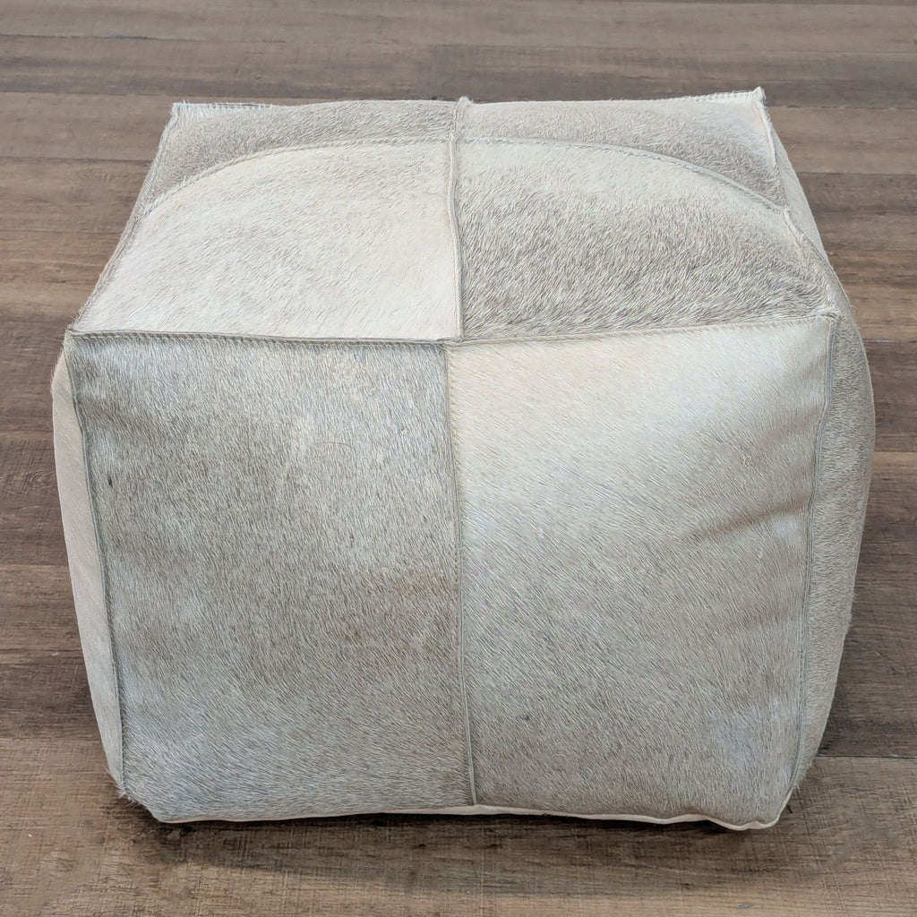 1. CB2 cube pouf ottoman with pale patchwork cowhide upholstery, shown on a wood floor, category Stools, Ottomans & Benches.